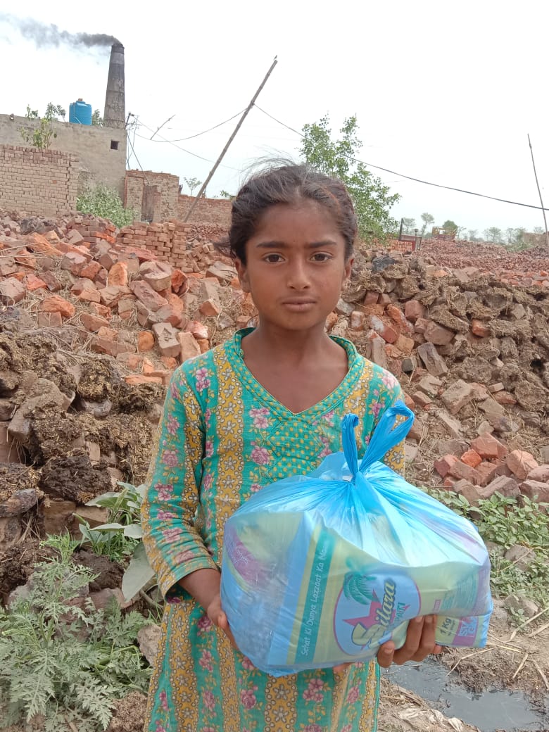 A young girl from a brick kiln community holding a bag of food